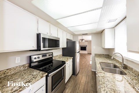 A kitchen with granite countertops and white cabinets.