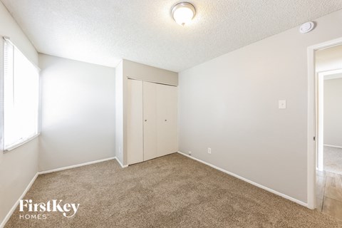 A bedroom with a carpeted floor and a closet.