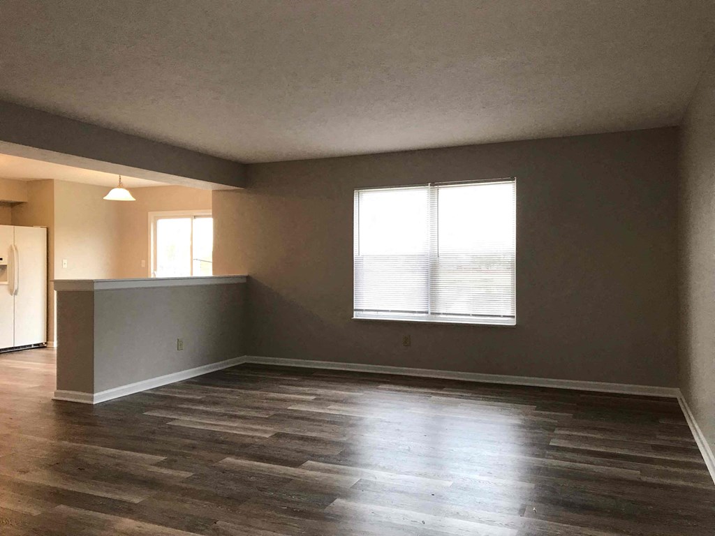 an empty living room with wood floors and a window