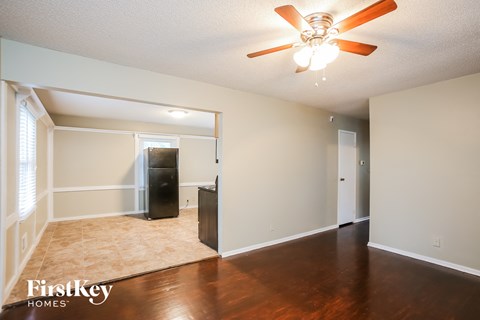 A room with a ceiling fan and a rug on the floor.