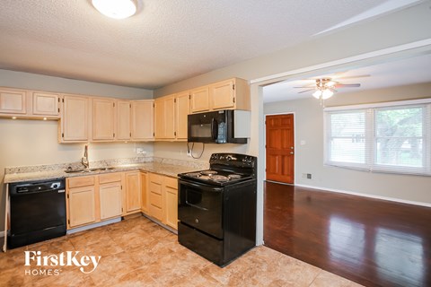 A kitchen with wooden cabinets and black appliances.