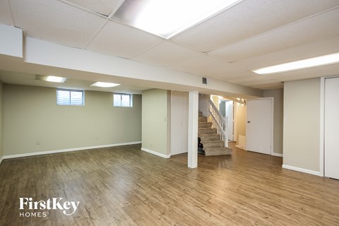A spacious room with wooden floors and a staircase leading to another room.