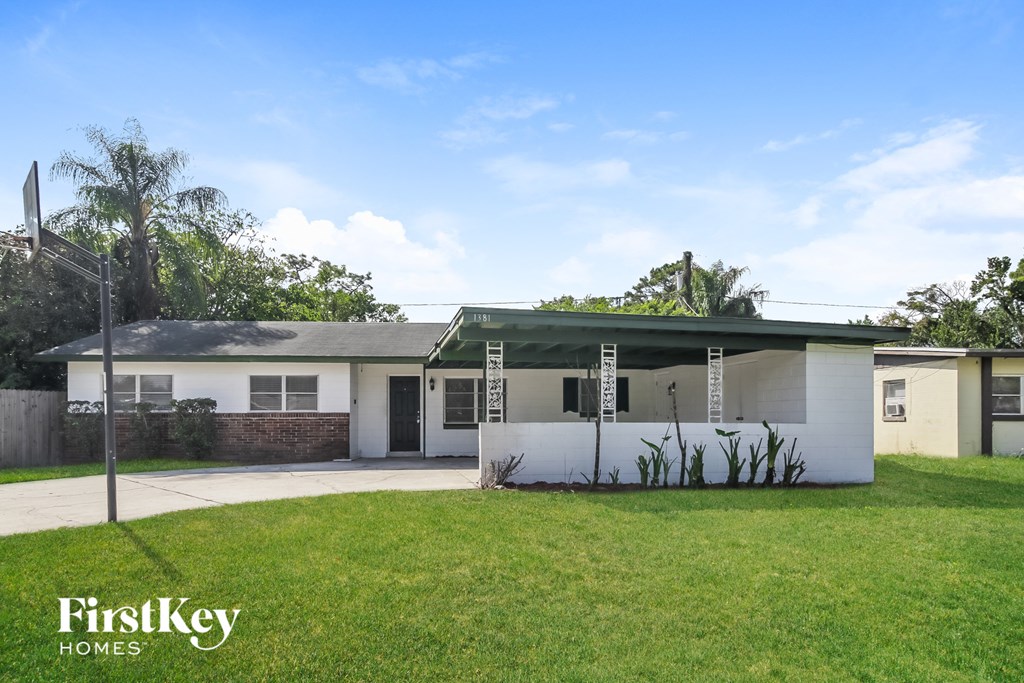 a white house with a green lawn and a driveway
