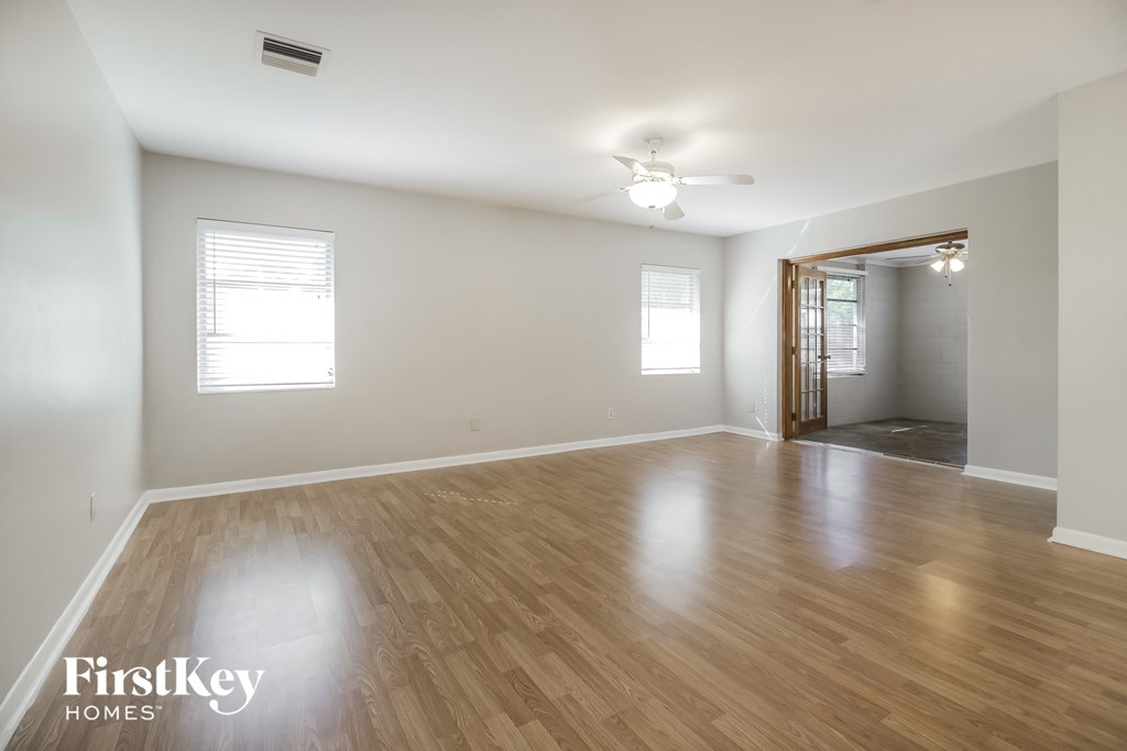 an empty living room with wood flooring and a ceiling fan