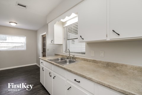 a kitchen with white cabinets and a sink and a window