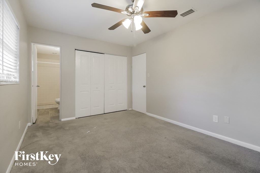 a empty living room with a ceiling fan and a closet