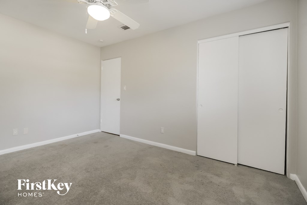 a bedroom with two white closets and a carpeted floor