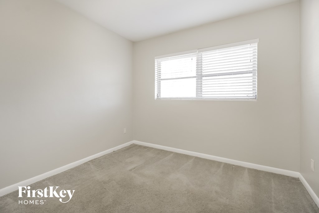 a bedroom with a window and a carpeted floor