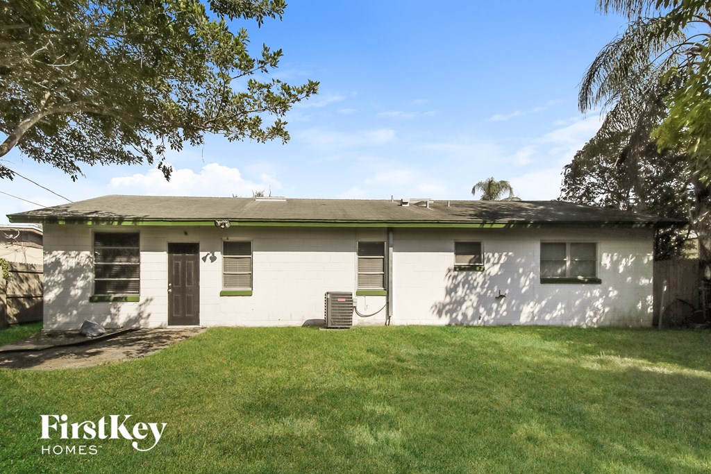 a white house with a green lawn and a tree