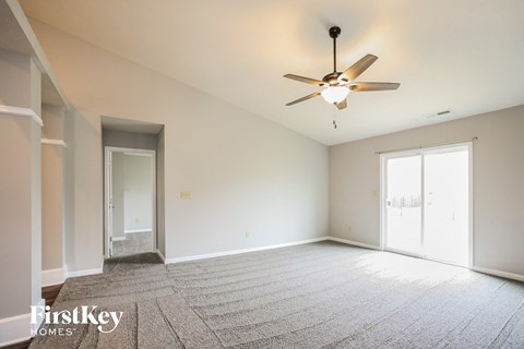 A spacious room with a ceiling fan and carpeted floor.