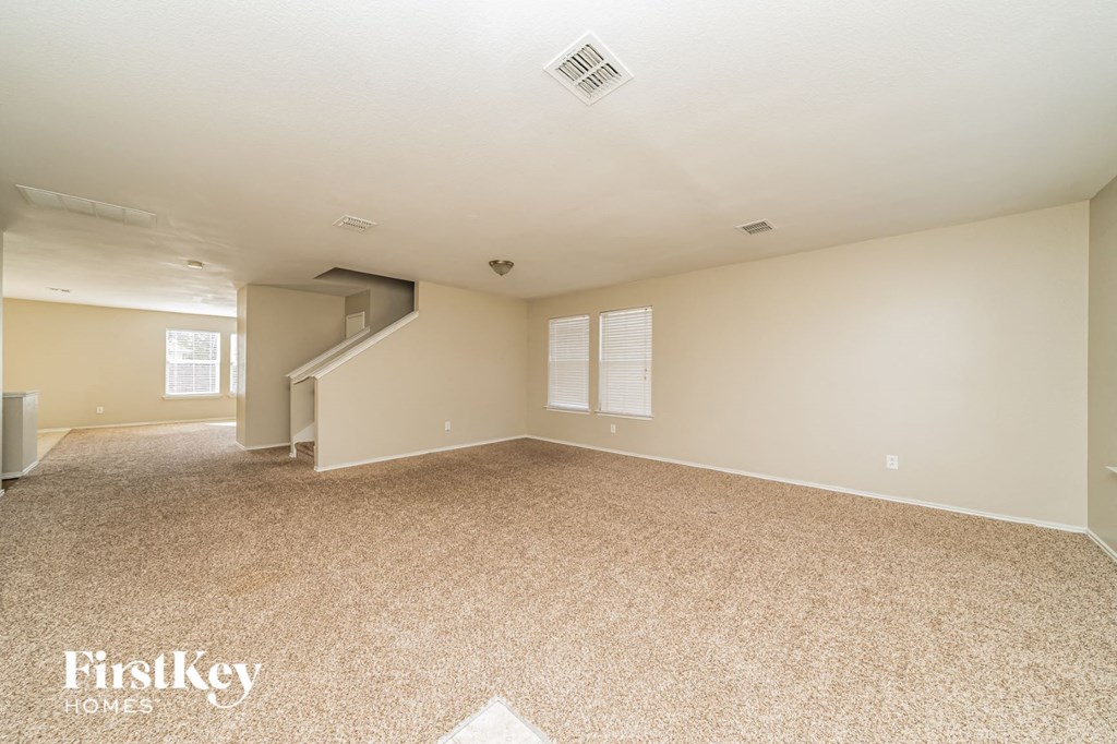a spacious living room with carpet and a staircase