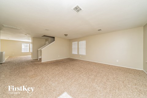 a spacious living room with carpet and a staircase