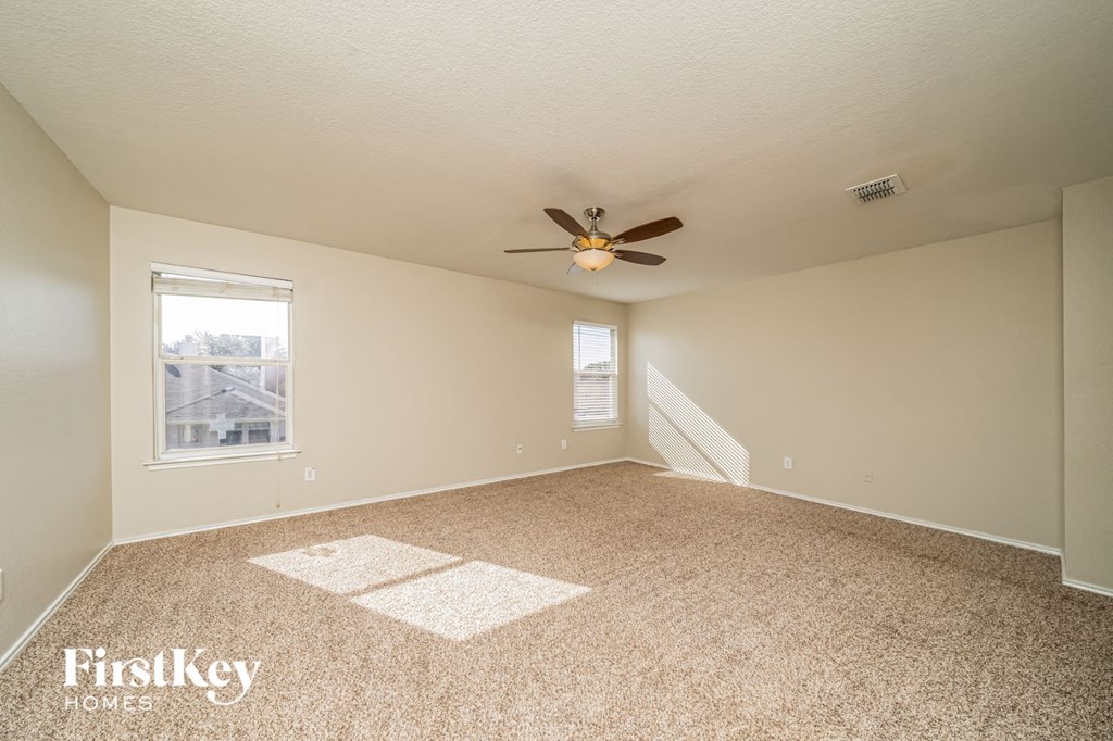 an empty living room with a ceiling fan and a window