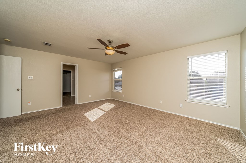 an empty living room with a ceiling fan and a window