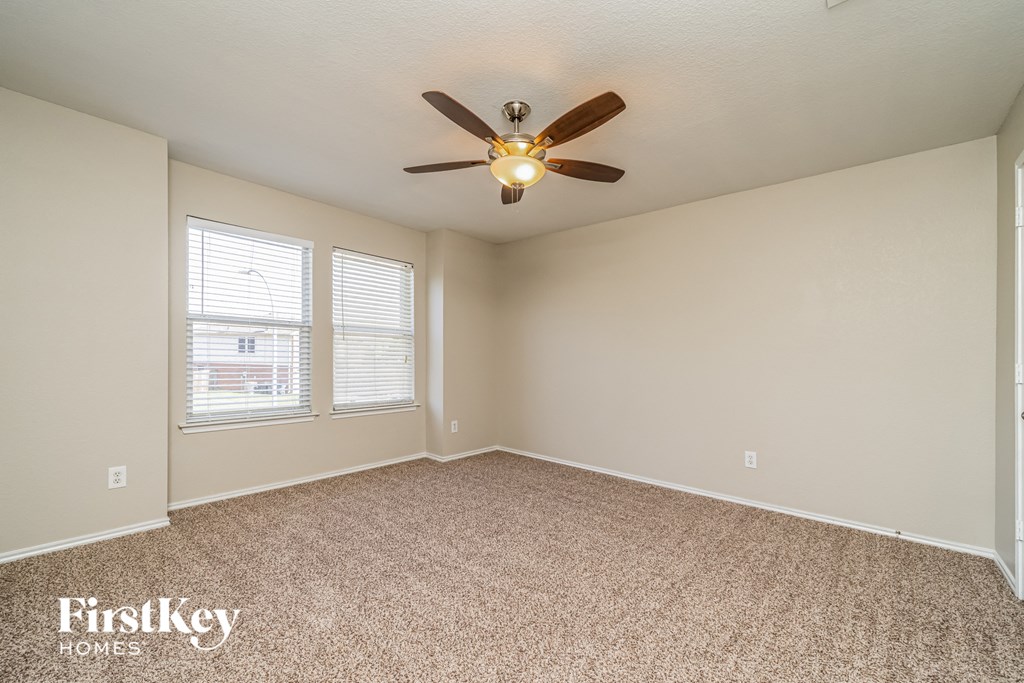 the spacious living room with ceiling fan and carpet