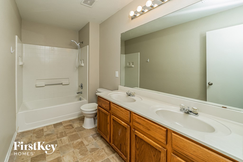 a bathroom with a large mirror and a sink and a toilet