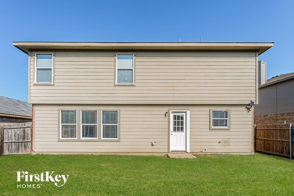 the front of a tan house with a white door and a green lawn