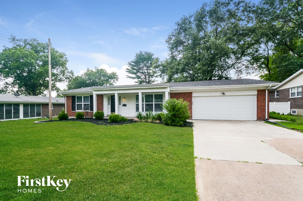 a white and brick house with a lawn and a driveway