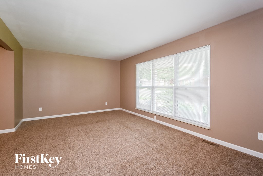 an empty living room with a large window and carpet