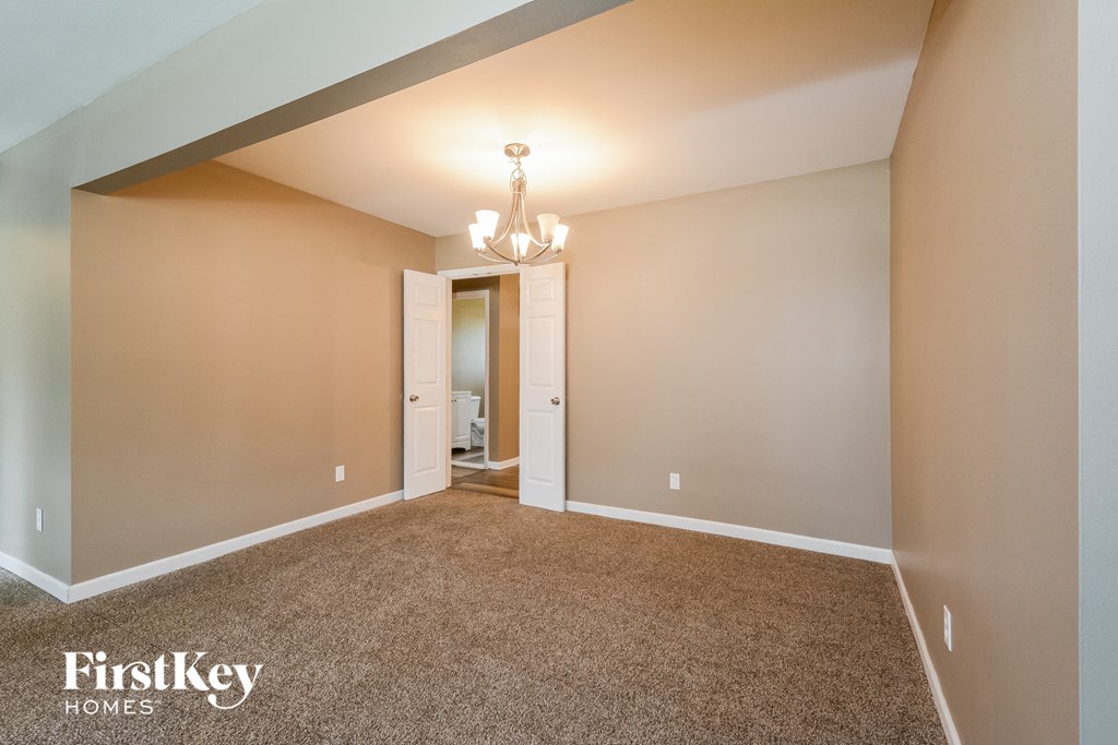 a spacious living room with carpeting and a chandelier