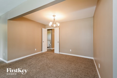 a spacious living room with carpeting and a chandelier