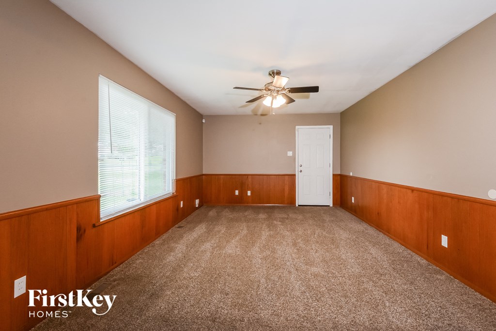 an empty living room with a ceiling fan and a window