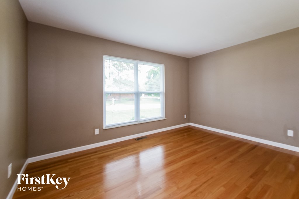 an empty room with wooden floors and a window
