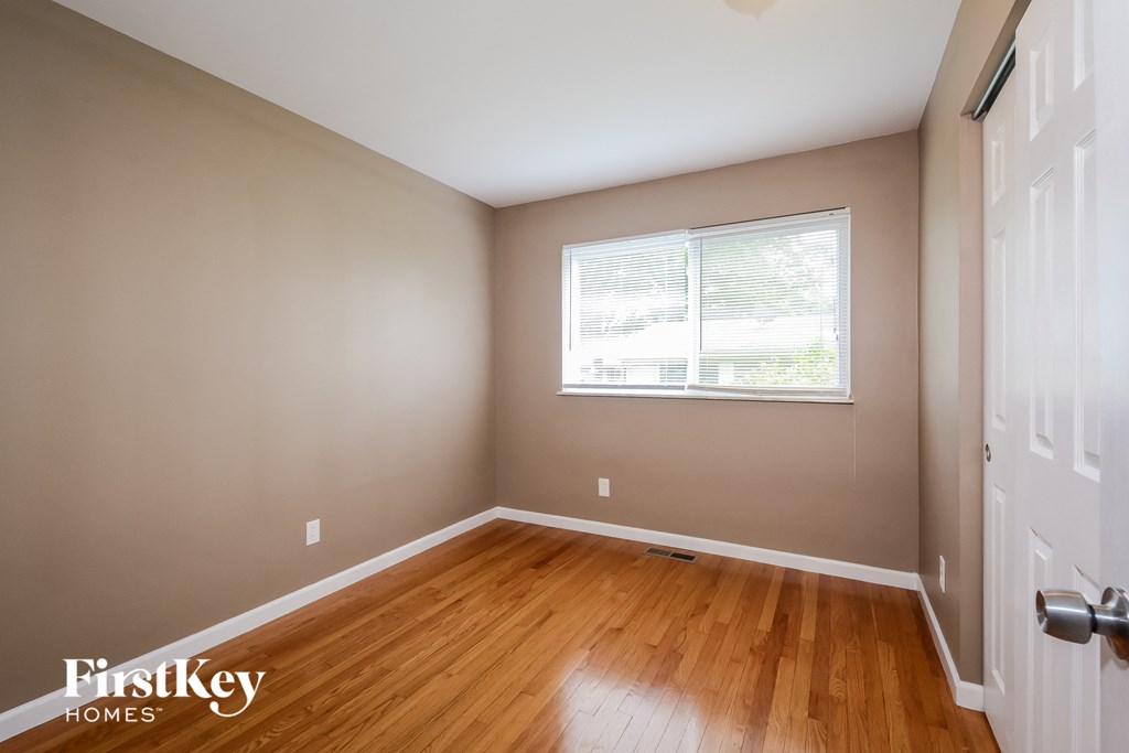 a bedroom with wood floors and a window