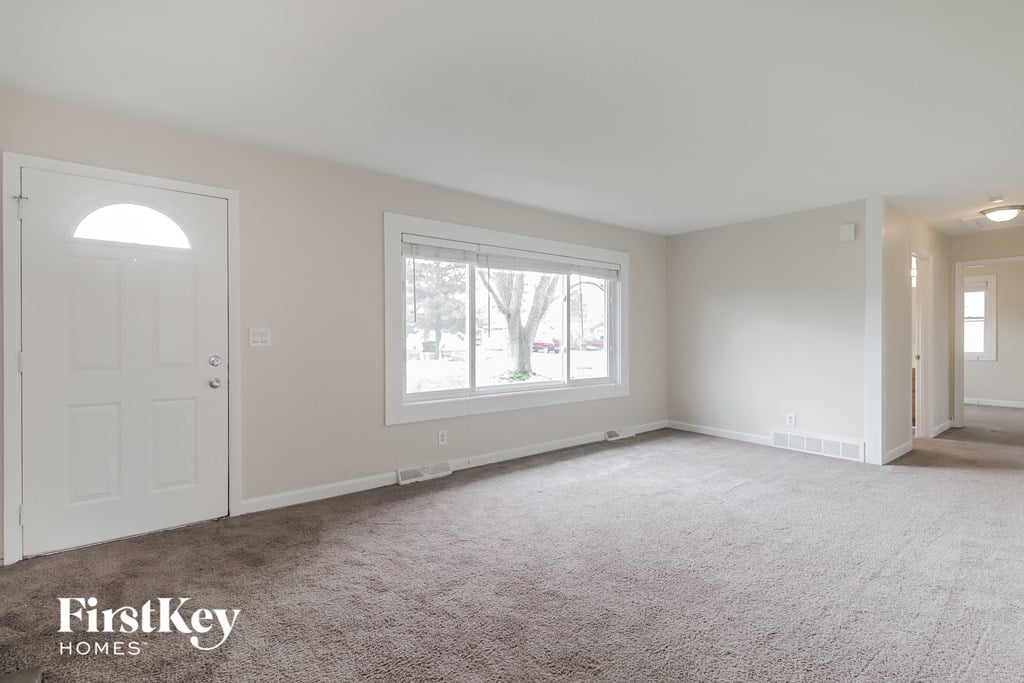 A spacious room with a carpeted floor and a large window.