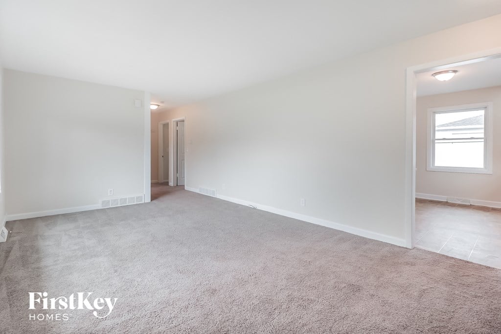 A spacious room with a carpeted floor and a doorway leading to another room.