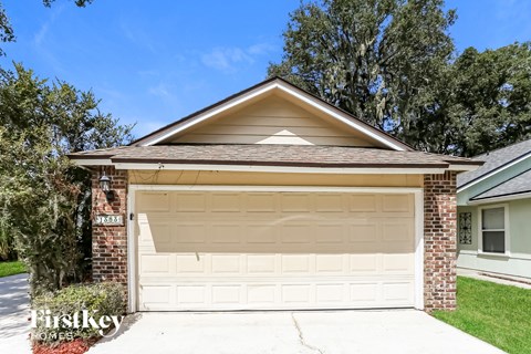 a white garage door in front of a brick house