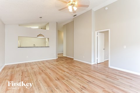 the living room and dining room with wood flooring and a ceiling fan