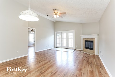 an empty living room with a fireplace and wooden floors