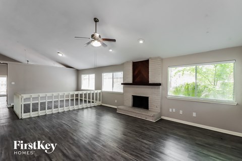A spacious living room with a fireplace and a ceiling fan.
