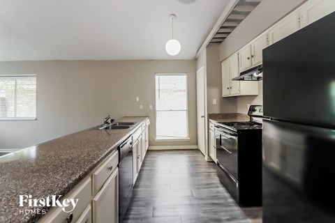 A kitchen with a black refrigerator and granite countertops.
