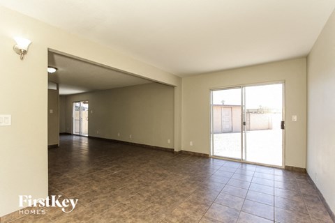 A spacious room with tiled flooring and a sliding glass door leading outside.