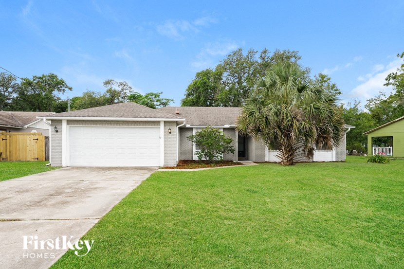 a white house with a palm tree in front of a lawn