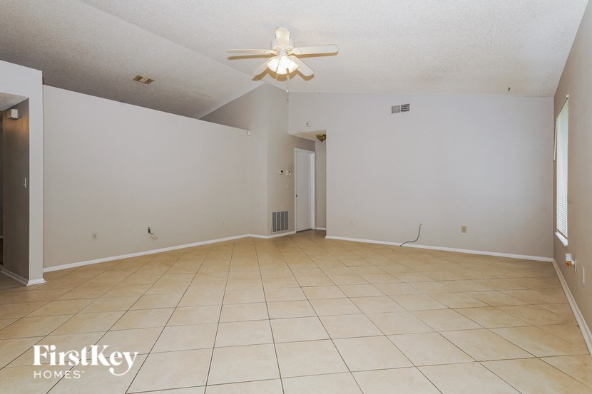 the living room and dining room of an empty house with a ceiling fan