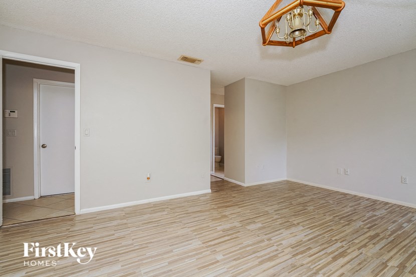 the living room and dining room with wood flooring and a chandelier
