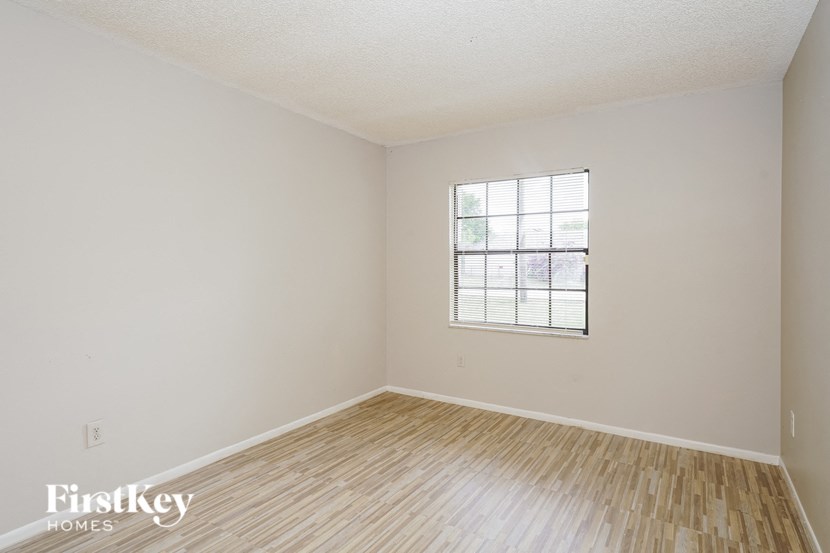 a bedroom with wood floors and white walls and a window