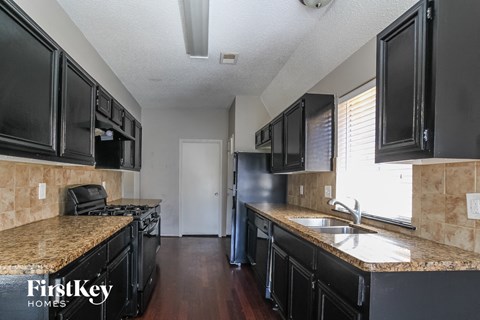 a kitchen with black cabinets and granite counter tops and a sink