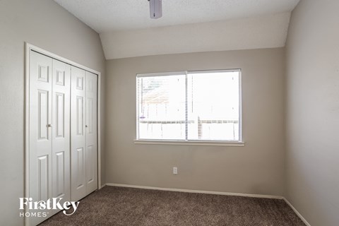 a bedroom with a large window and carpeted flooring