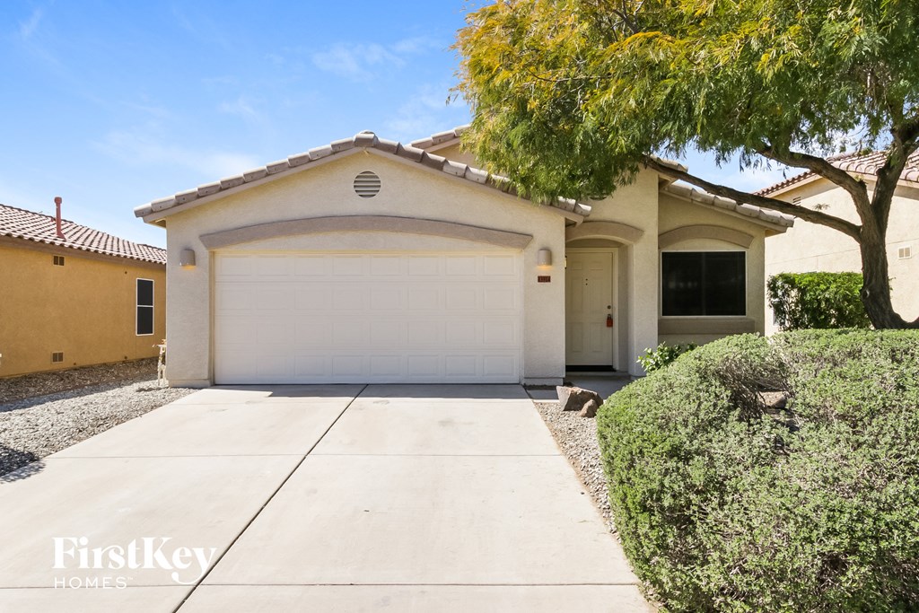 A house with a white garage door and a tree in front.