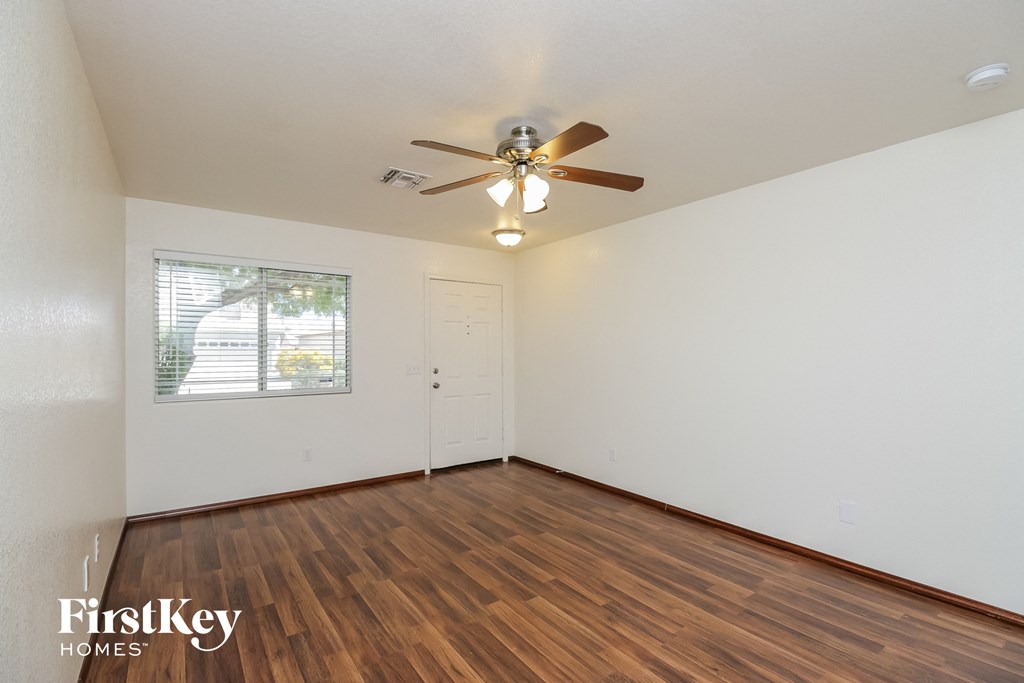A room with a ceiling fan and wooden flooring.