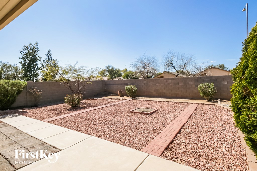 A backyard with a gravel area and a concrete walkway.