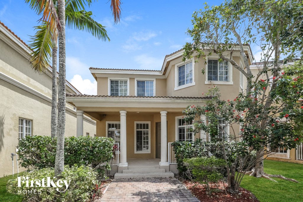 a house with palm trees and a sidewalk in front of it