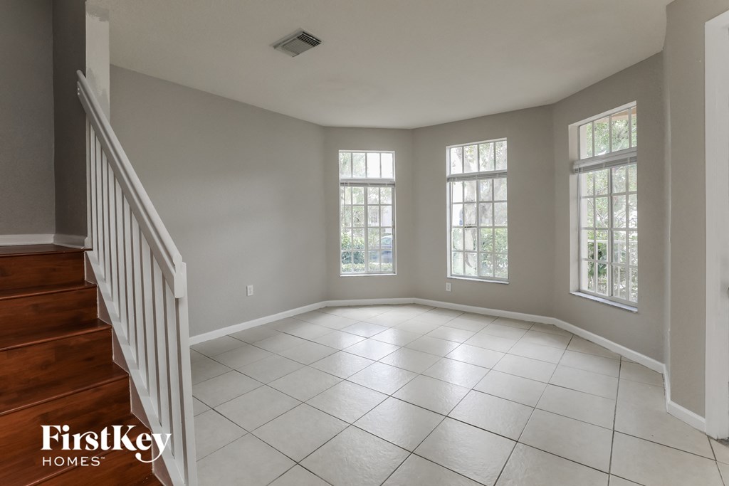 an empty living room with three windows and a staircase