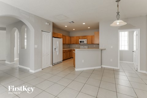 a large kitchen with white tile flooring and wooden cabinets
