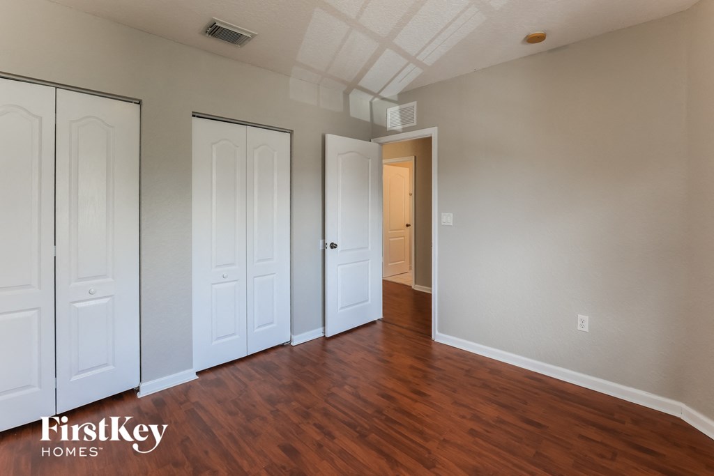 a bedroom with three closets and a hard wood floor