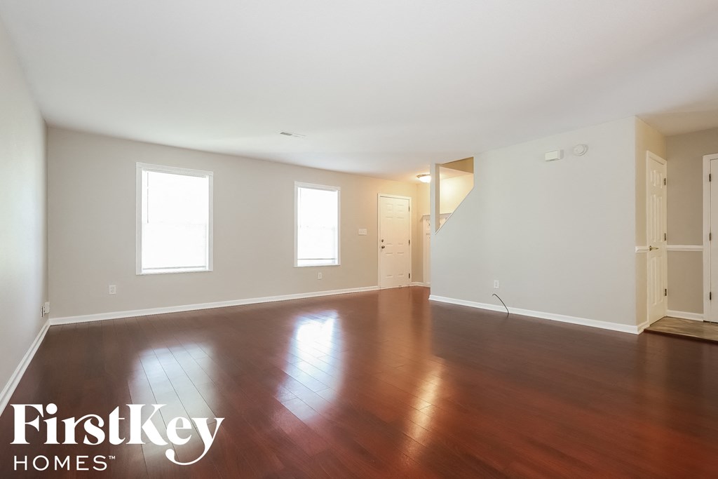 A room with wooden floors and white walls, with a FirstKey Homes logo in the corner.
